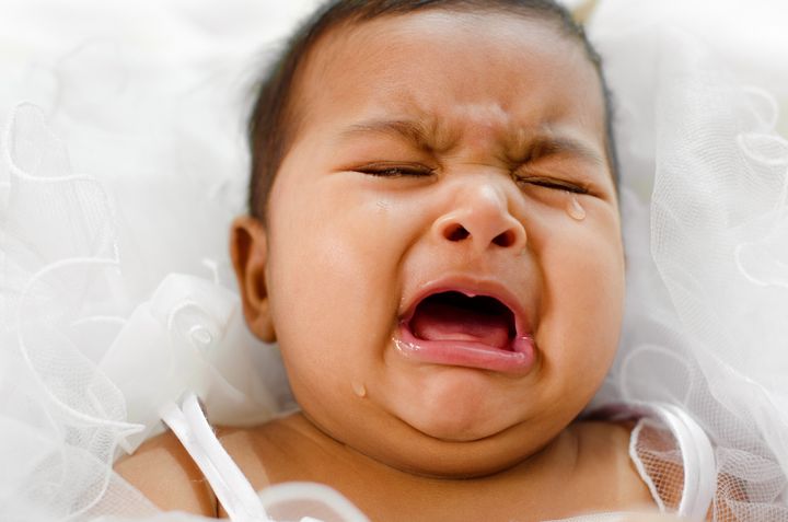 Crying Indian baby girl lying on bed