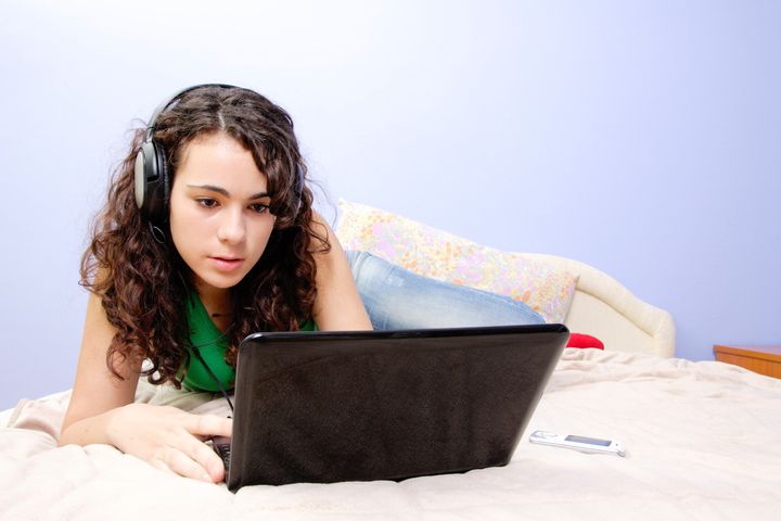 Teen girl in her bed looking on her laptop