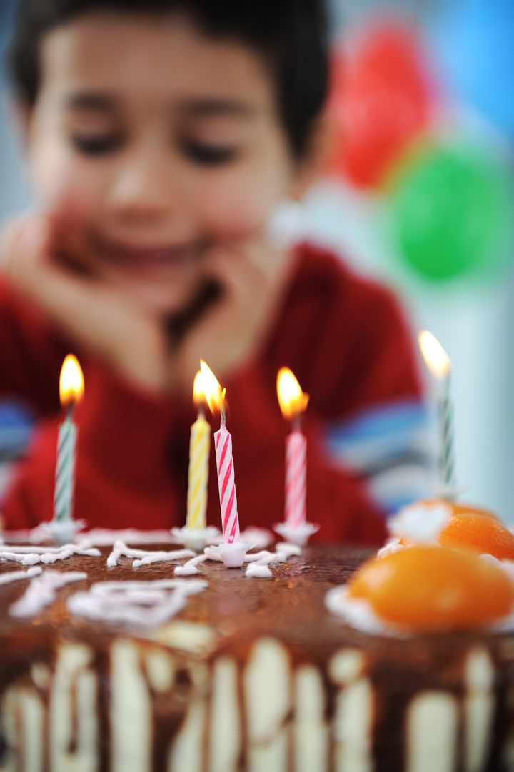 Boy blowing candles on cake, happy birthday party