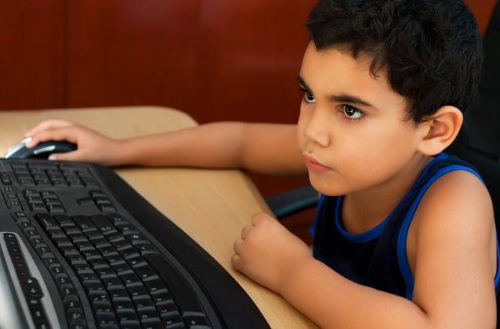 Small latin boy working on a computer or browsing the web at home