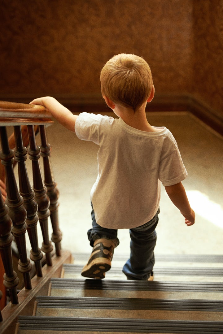 Rear view of a young boy walking down the stairs at home