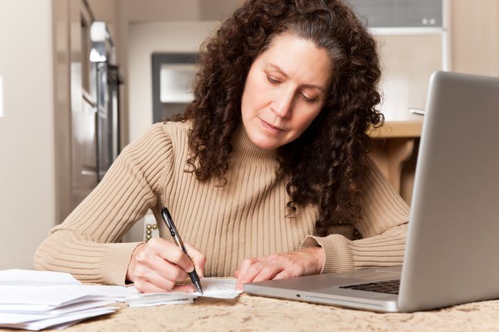 A shot of a middle age caucasian woman paying bills at home