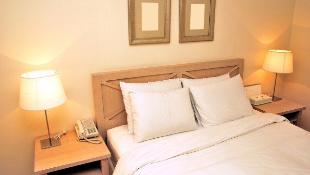 Twin beds with table lamps lighted up in a high class, dimly-lit hotel room