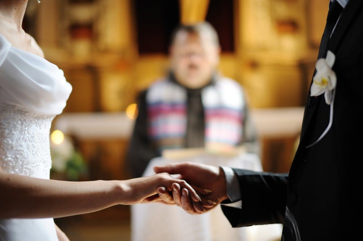 Bride and groom are holding each other's hands during church wedding ceremony