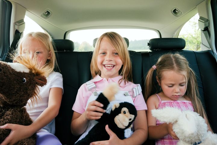 Family with three kids in a car, kids sitting on the backseats