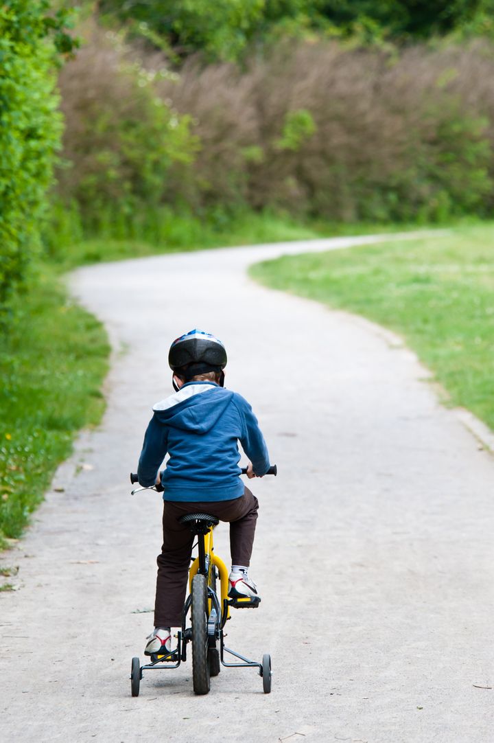 5 years old boy wearing safety bicycle helmet riding a bike