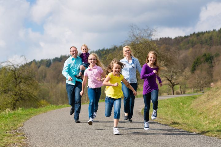 Family (mother, father and four children) is running outdoors in spring