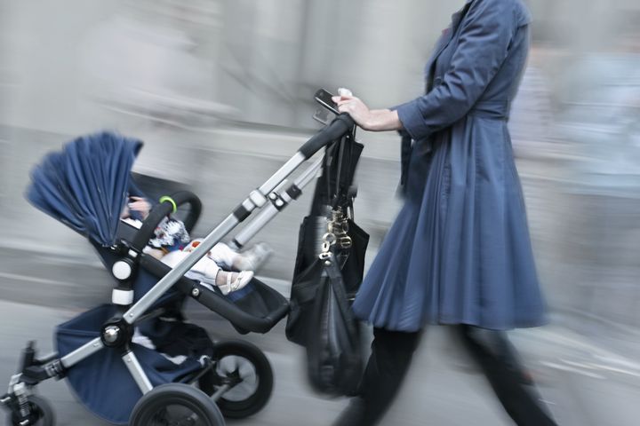 young parent with stroller rushing on the street in intentional motion blur