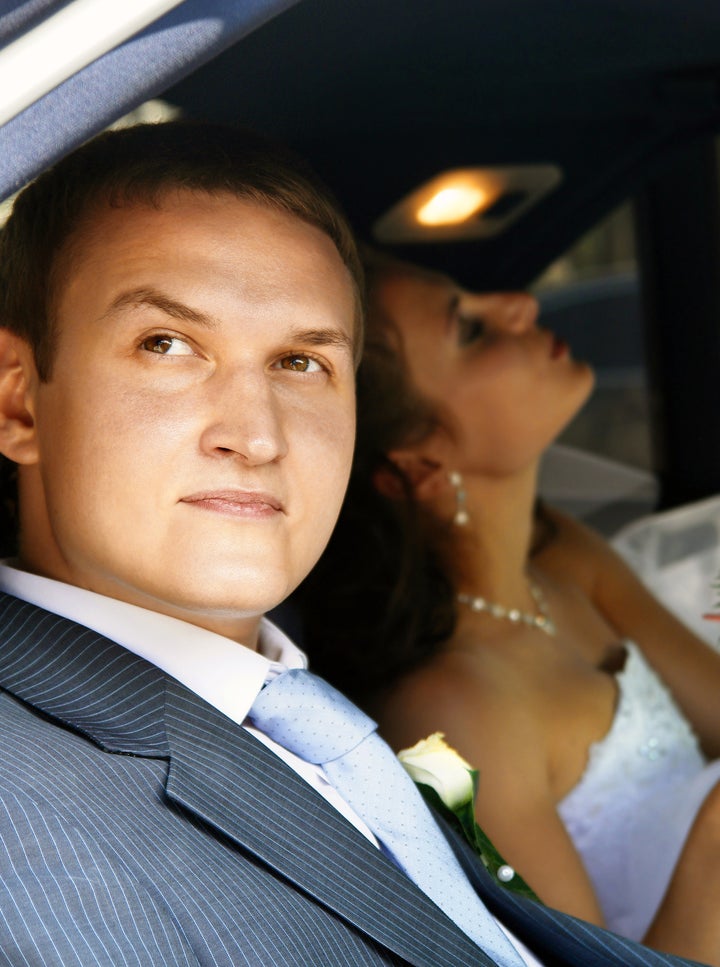 Groom and bride on the back seat of the car.