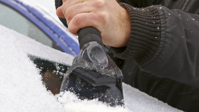 scraping snow and ice from the car windscreen