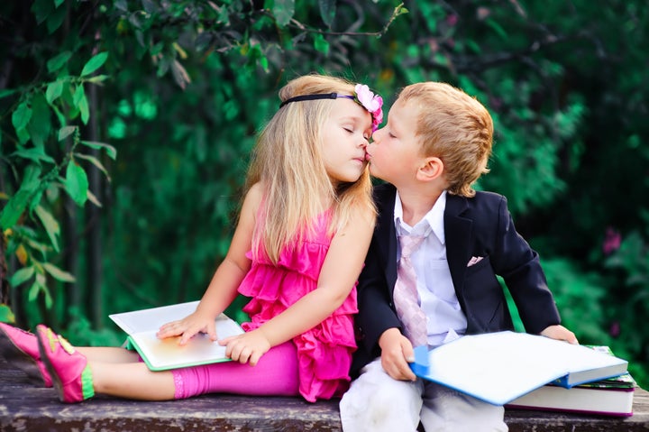 Adorable happy kids outdoors on summer day, little boy kissing a girl