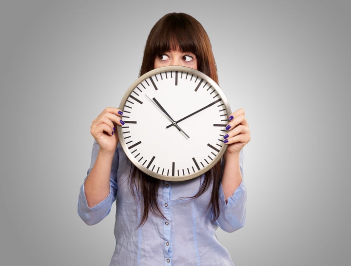 a young girl holding a clock on ...