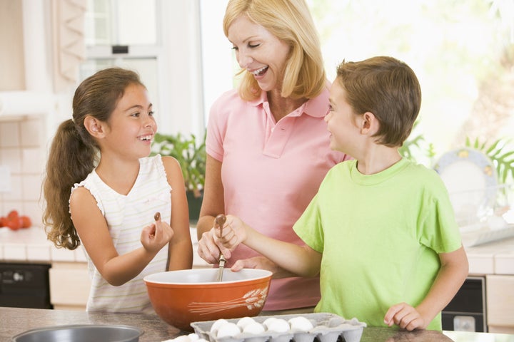 Woman and two children in kitchen baking and smiling