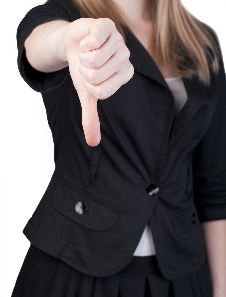 Attractive blonde woman in professional business suit pointing her thumbs down