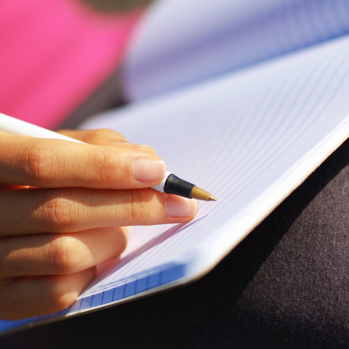 Girl writing in notebook in a field.