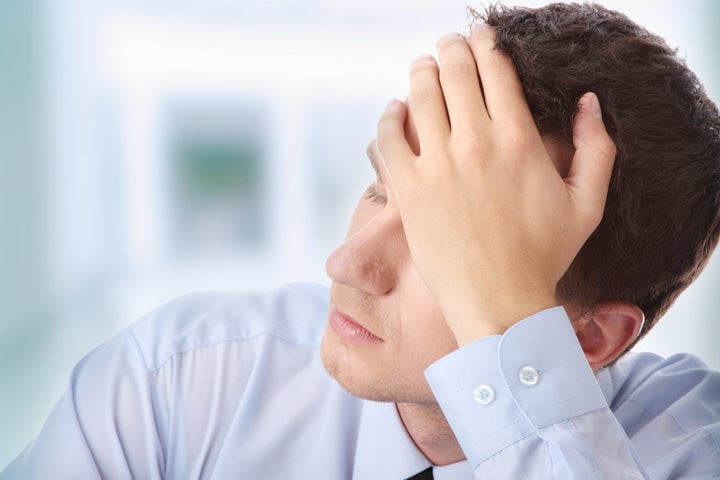 Businessman in depression with hand on forehead