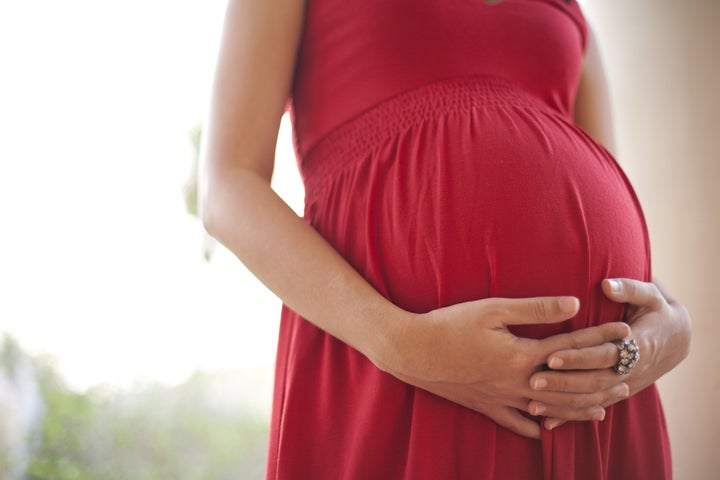 Image of pregnant woman touching her belly with hands