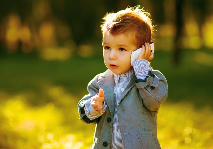 ittle boy in green grass call by phone