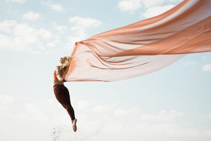 Girl dancing with long orange transparent cloth