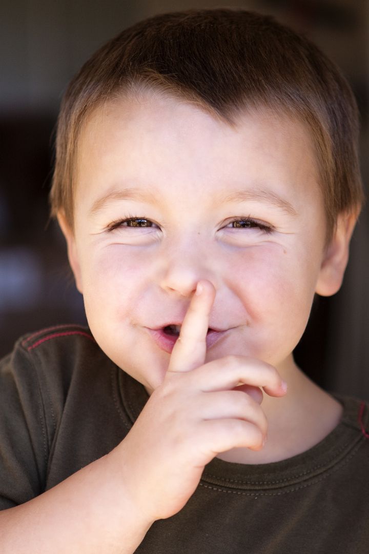 Adorable little boy with finger to his lips signaling for quiet