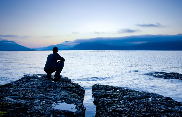 Man sitting on a small island watching the sunrise, slight cooling tone added.