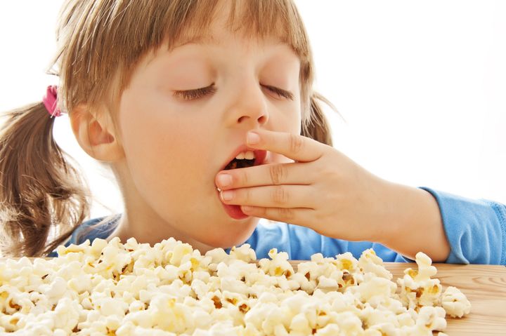 little girl eating popcorn isolated on white background