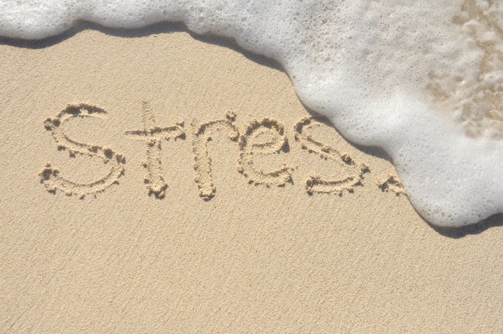 Relieving Stress, the Word Stress Being Washed Away by a Wave on a Beach