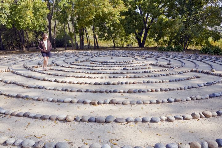 In deep thought, a woman walks a forest labyrinth