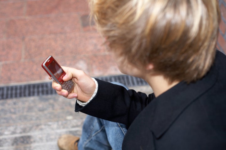 Teenage boy text messaging with mobile phone, high-angle view