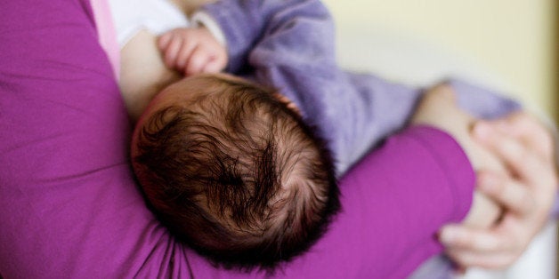 Mother holding and feeding newborn baby,rear view.