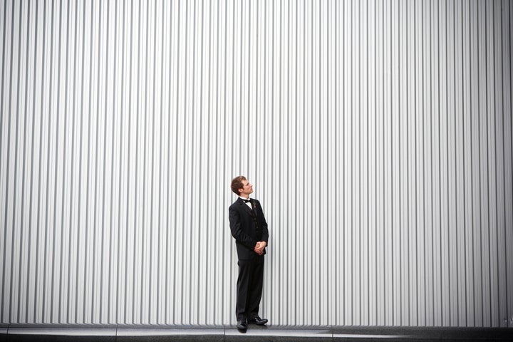 Uncertain groom standing near wall