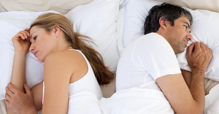 Upset couple sleeping separately on their bed