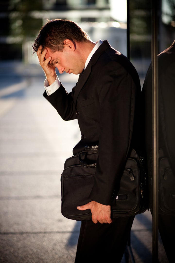 Desperate businessman leaning on an office building