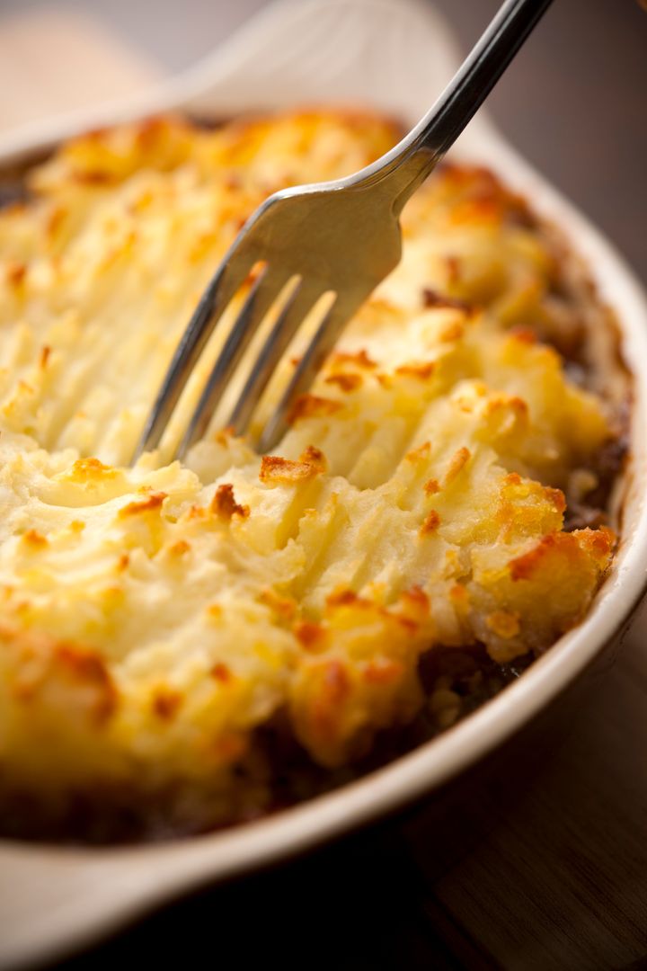A home baked cottage pie with fork, shallow focus, rustic style.