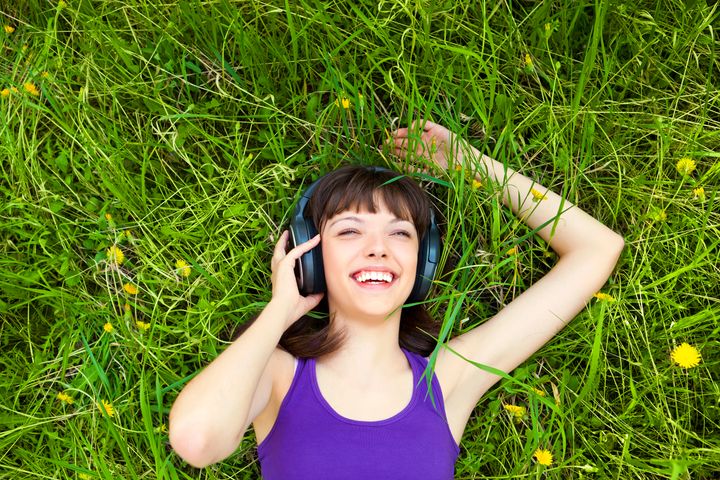 girl listening to music while lying in the grass