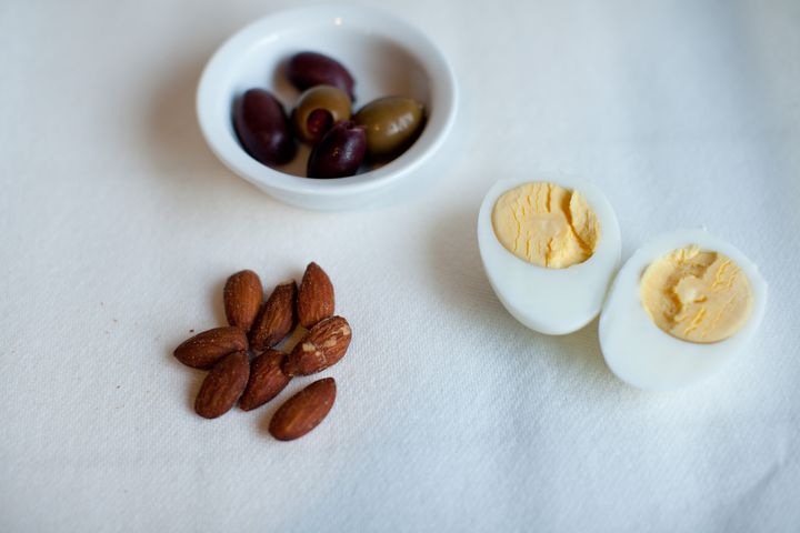 Olives, almonds, and hard boiled egg on white background.