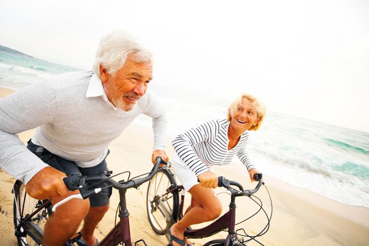Senior couple driving bicycles on the beach
