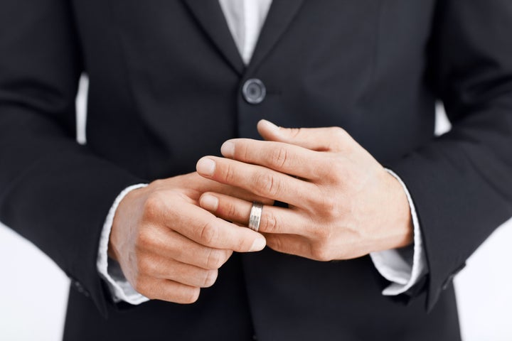 Cropped view of a married man's hands as he removes his wedding ring