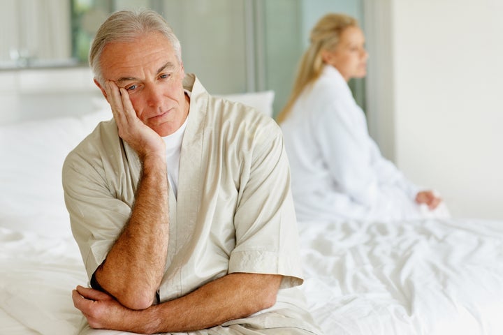 Senior man and his wife in a conflict sitting separately on the bed