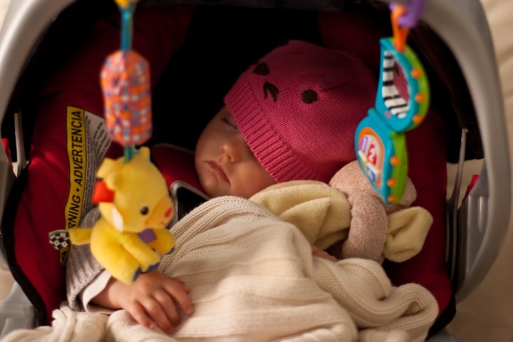 Little baby girl sleeping in car seat.