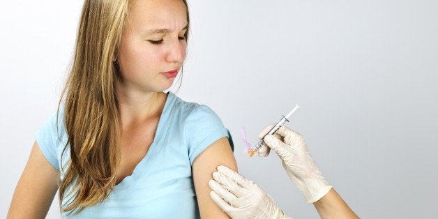 Teenage girl getting flu shot needle vaccination in arm