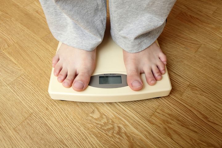 Weighloss - young man on a weighing scale