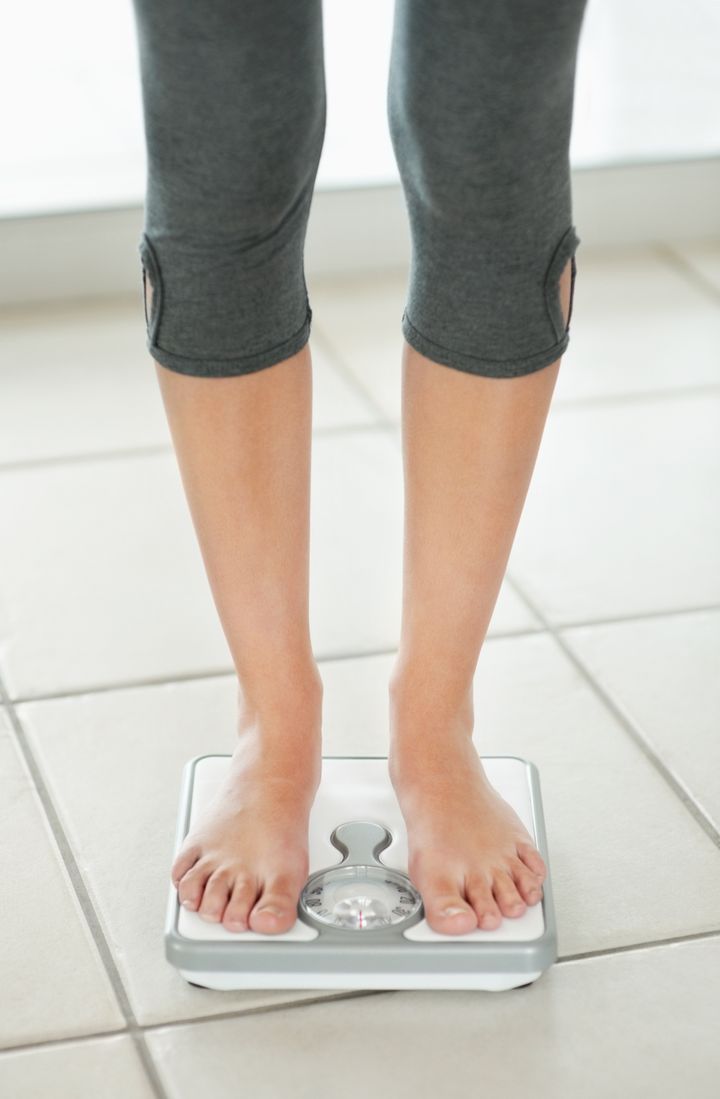 Low section of a young standing on a weighing scale