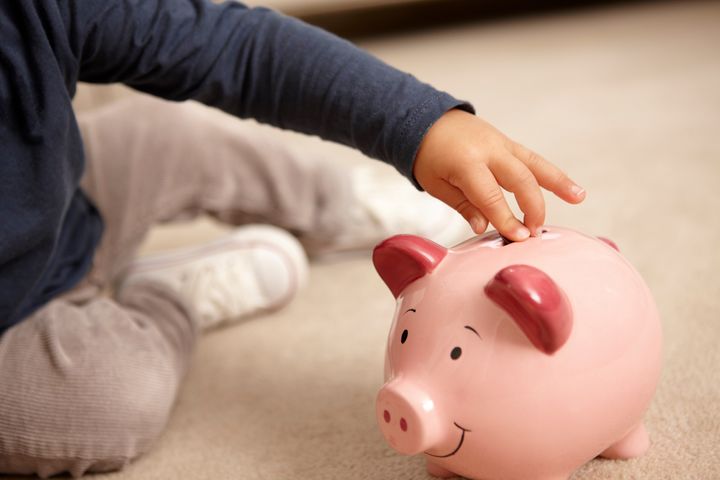 Close up of boy putting coins in piggy bank