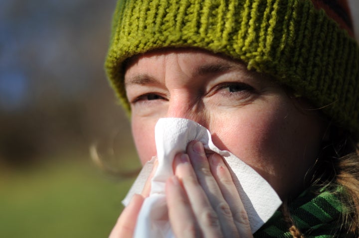 woman blowing her nose into...