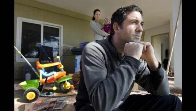 Young parents and their daughter stand beside cardboard boxes outside their home. Concept photo illustrating divorce, homelessness, eviction, unemployment, financial, marriage or family issues.