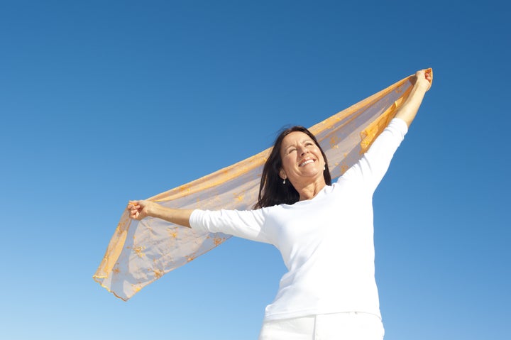 Happy, confident and attractive senior woman with positive attitude, isolated with blue sky as background and copy space.