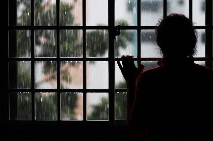 Woman looking at rain fall from window.