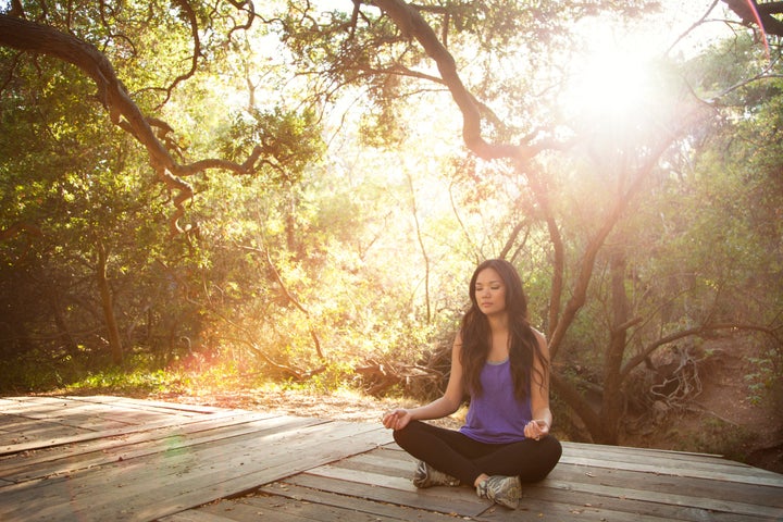 Young Woman Meditating In Woods