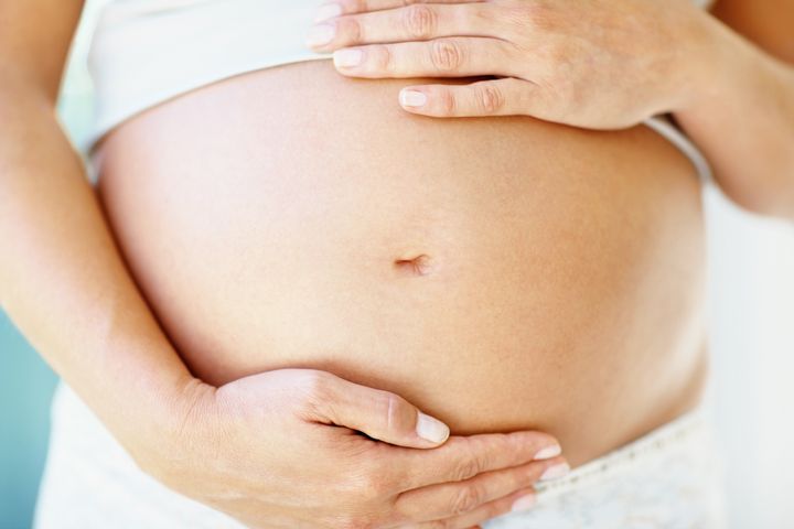 Mid section closeup of a pregnant woman holding her tummy